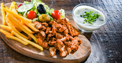 Kebab served with french fries, vegetable salad and tzatziki