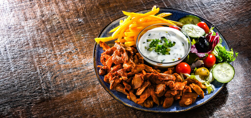 Kebab served with french fries, vegetable salad and tzatziki