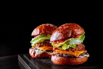 two barbecue pulled beef burgers with vegetables on dark background