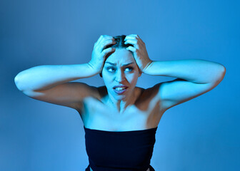 Head and shoulders close up portrait of pretty girl with expressive facial expressions, with  colourful neon gel lighting, isolated on studio background.