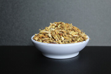 Dried granules of Aniseed, or Pimpinella Anisum seed, or Adas Manis, inside a bowl. Isolated on black background