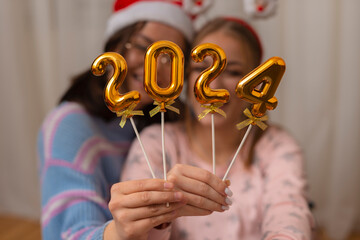 Two woman holding 2024. number for new year.