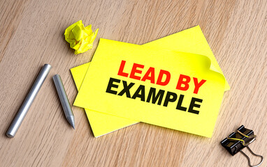 LEAD BY EXAMPLE text on yellow sticky on wooden background
