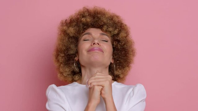 Woman beg with cute smile, she asks for help, cute curly haired female, next to pink wall