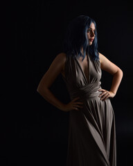  close up portrait of pretty girl with blue hair wig & elegant gown with expressive facial expressions & gestural arm poses. colourful neon gel lighting, isolated on studio background.