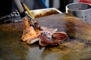 octopus grilled on a hot griddle in street food festival, cooking perform