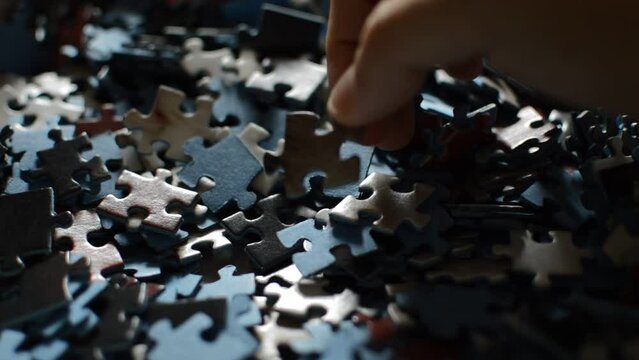 man's hand looking for the perfect jigsaw puzzle piece.