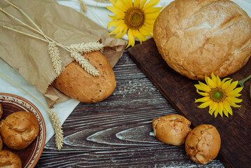 wheat bread with flax seeds, buns or pies, sunflower on a brown wooden background, home baking