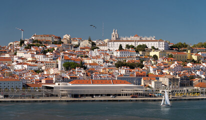 Naklejka premium Sailboat on Lisboa Tagus River, waterfront and cityscape. Vacation, leisure, travel concept.