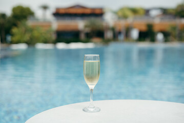 champagne glass on the edge of infinity swimming pool. Drink, vacation and summer concept.