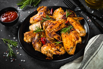 Grilled chicken wings with spices in black plate.