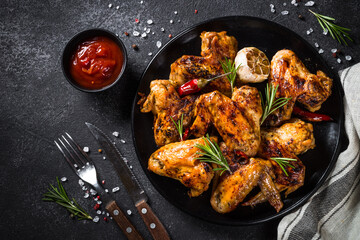 Grilled chicken wings with spices at black table. Top view with space for design.