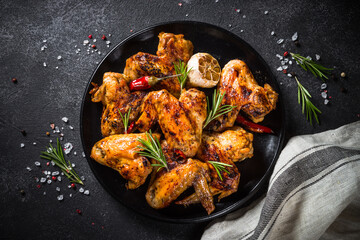 Grilled chicken wings with spices at black table. Top view with space for design.