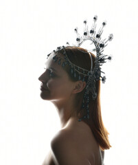 Close up portrait of beautiful girl in side profile, wearing an ornate silver crown headpiece,...