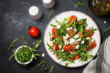 Arugula salad with tomatoes, blue cheese and walnuts. Healthy vegetarian dish. Top view image, close up.