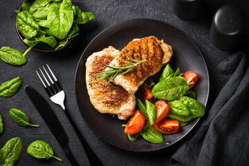 Grilled Meat. Pork steaks with fresh salad. Top view image at black table. keto diet lunch.