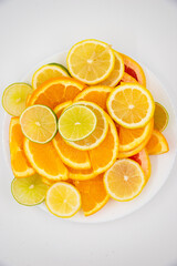 Bowl with healthy fresh citrus fruits orange, lemon, lime, grapefruit on white background. Top view with copy space. Lying flat