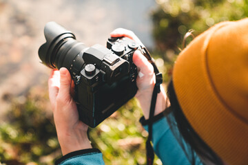 Outdoor photographer taking landscape photos using digital camera. Side view of man using dsrl...