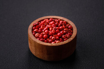 Allspice peas in a wooden bowl on a black concrete background