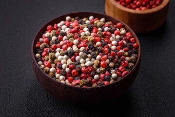 Allspice peas in a wooden bowl on a black concrete background