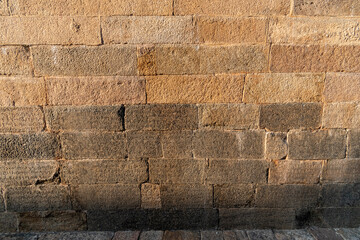 Texture and detail of stone masonry of an ancient Hindu temple with Tamil inscriptions carved on the wall.
