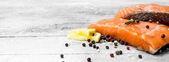Raw salmon fish steaks with spices and lemon wedges.