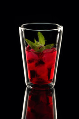 red drink with ice on a black background with reflection