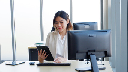 Young female employee working at the office using laptop and tablet to work.