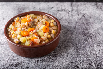 Spelled and legume soup served on an earthenware plate. Single balanced dish, suitable for a vegan diet, rich in vitamins, minerals and iron.