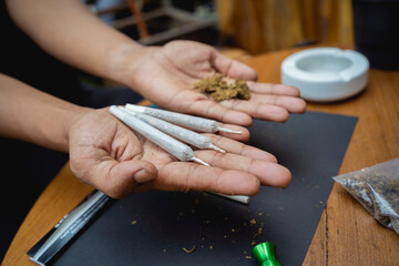 Young man making cigarettes with medical marijuana