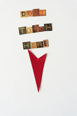 "dont touch here" composed of chipboard tiles with vintage style letters and retro red arrow on blank paper