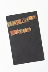 "naughty notes" composed of chipboard tiles with vintage style letters on blank black paper with lines