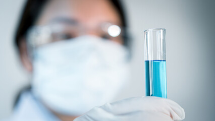 Asian woman Scientist experimental in laboratory with test tube and beaker for medical research