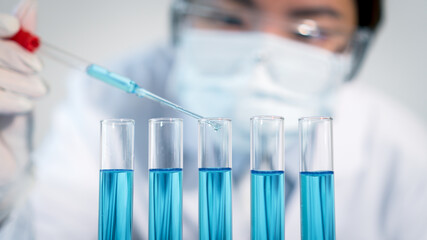 Asian woman Scientist experimental in laboratory with test tube and beaker for medical research