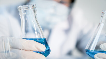 Asian woman Scientist experimental in laboratory with test tube and beaker for medical research