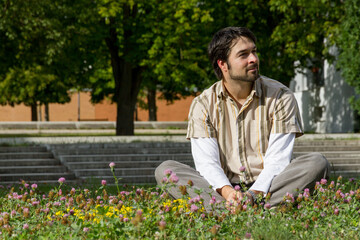 Naklejka na ściany i meble man sitting cross-legged in the sun in the grass of a park