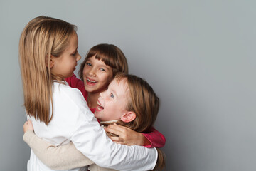 Laughing small girls children embracing on grey background portrait