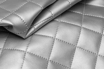 Quilted fabric sample with silver texture. Metallic leather background