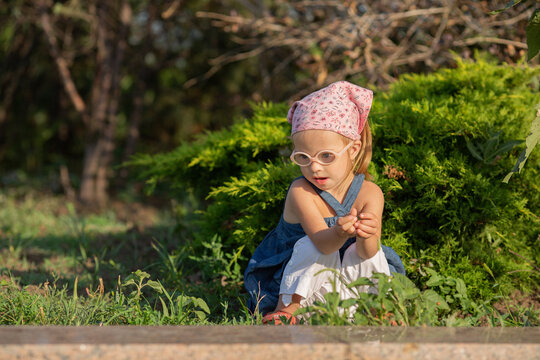 A girl with Down syndrome walks in the square. Taking the first steps