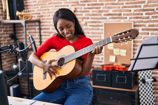 Young african american woman musician playing spanish guitar at music studio