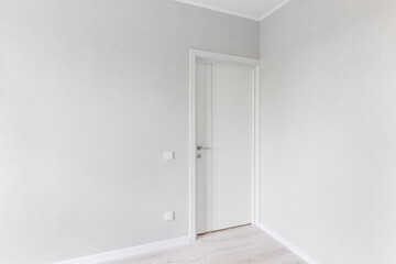 Modern white door. Grey wall with free space. Minimalist bright interior