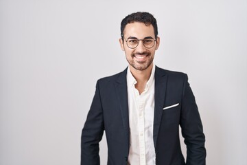 Handsome business hispanic man standing over white background with a happy and cool smile on face....