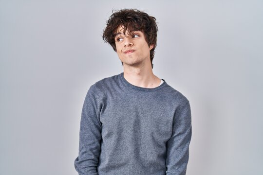 Young man standing over isolated background smiling looking to the side and staring away thinking.