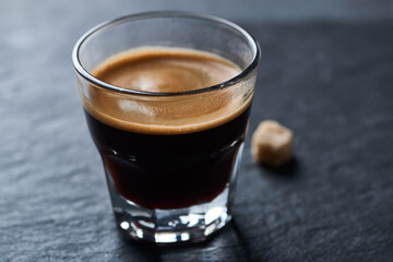 Coffee in glass cup on dark stone background. Close up.	