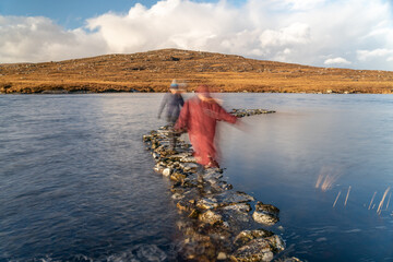 Stone Path on the Lake with blurred mum and daughter walking across the water.
