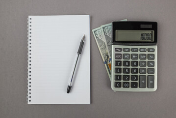 Top view of a calculator with dollars and a notepad