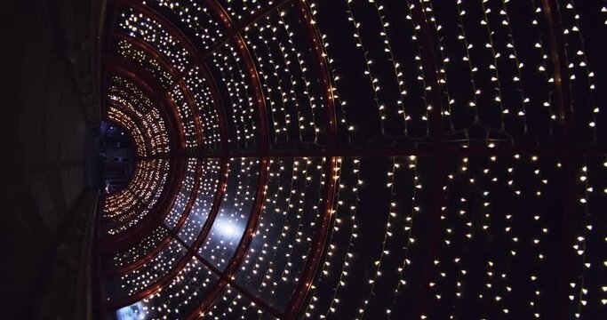 vectical video of festively lit underground passage tunnel with red frame arch and transparent dome and concrete staircase