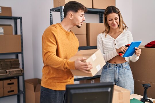 Young man and woman ecommerce business workers scanning package using touchpad at office