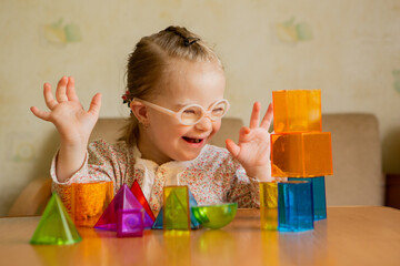 A girl with Down's syndrome lays out geometric shapes - obrazy, fototapety, plakaty