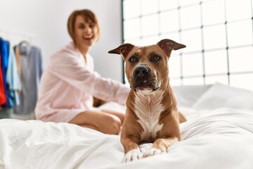 Young caucasian woman smiling confident sitting on bed with dog at bedroom